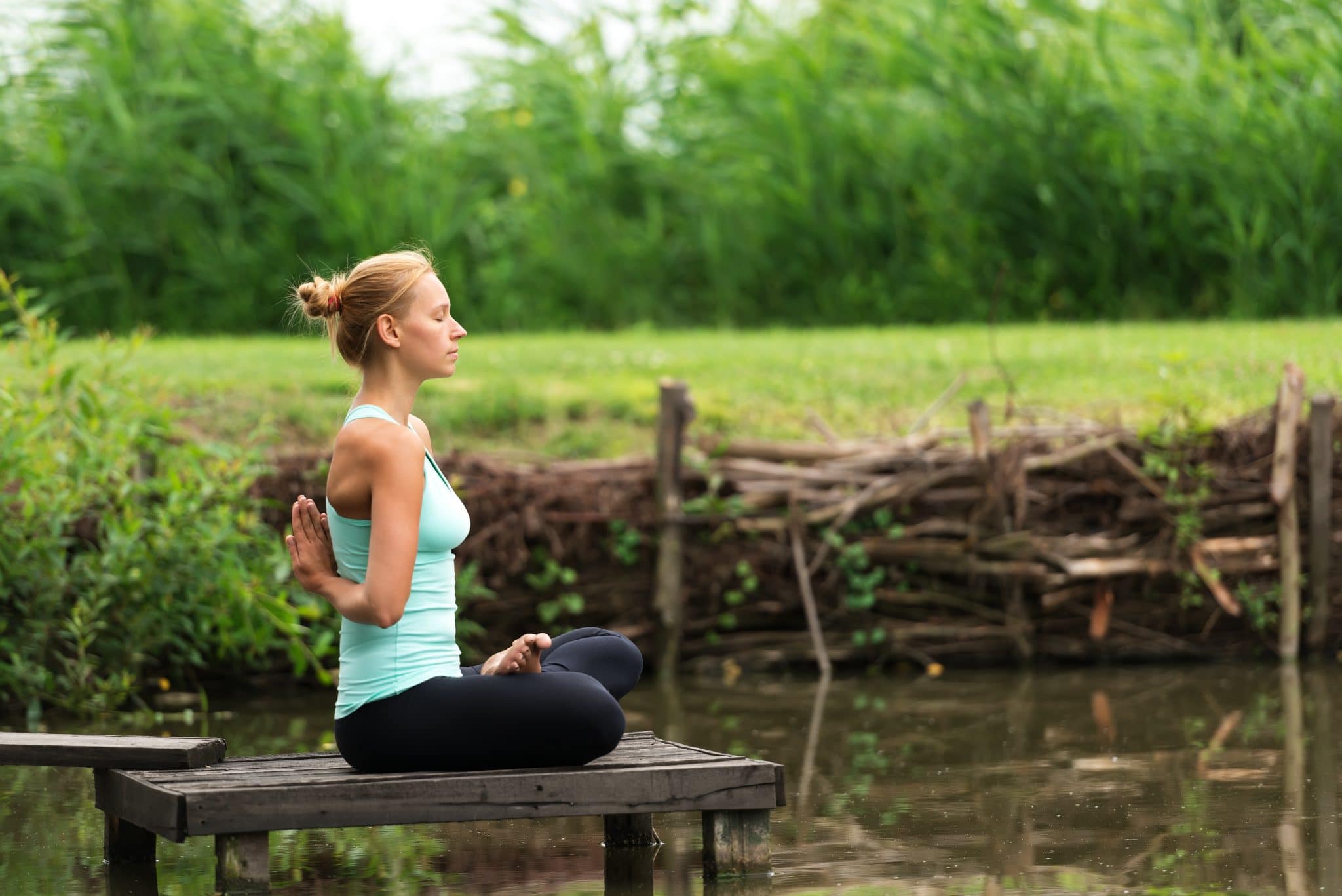 Woman meditating beside a lake | Moving Minds Hypnotherapy